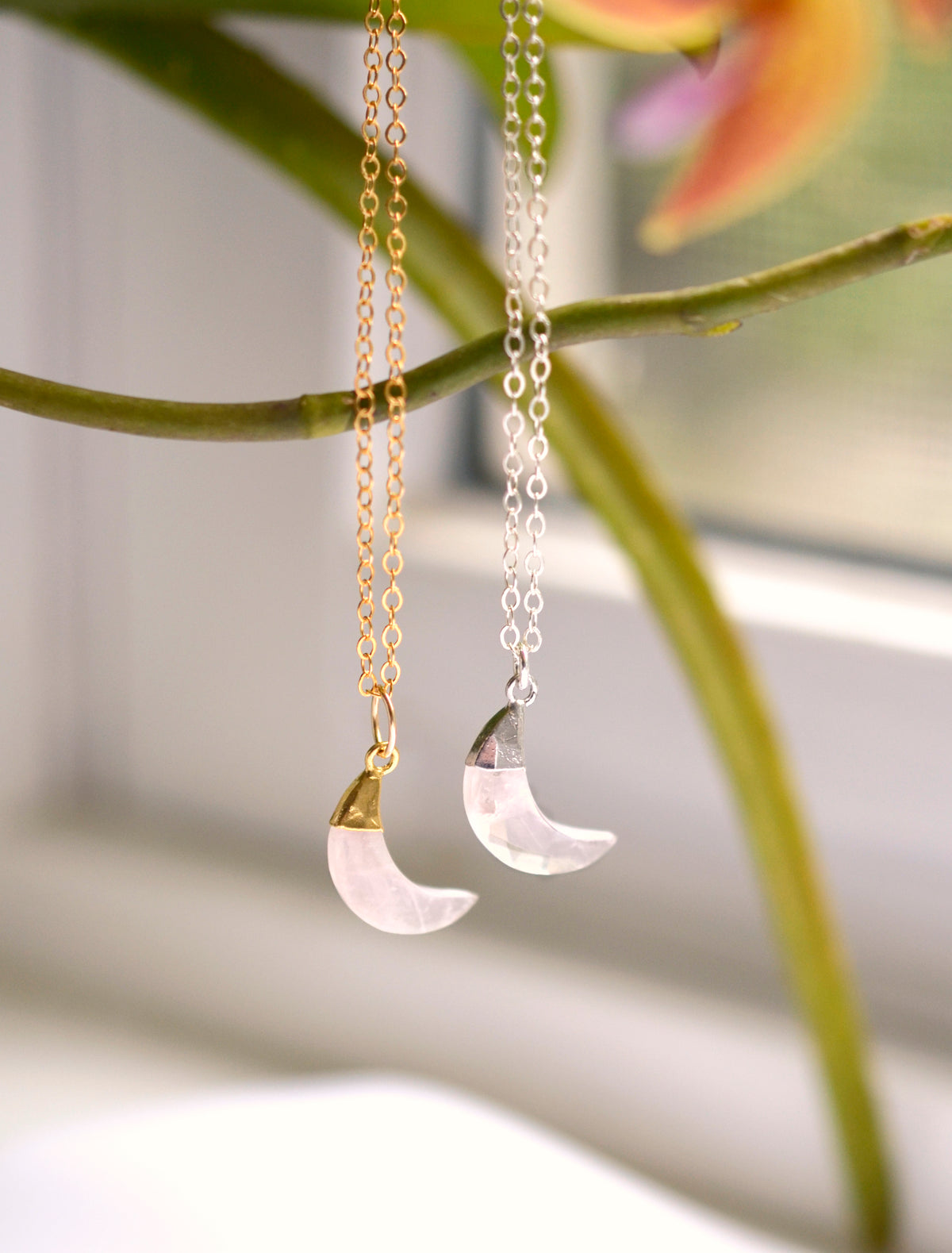 A close up of two rose quartz moon crescent necklaces in sterling silver and 14k gold filled. Each pendant is handmade by Gemnia in Connecticut.