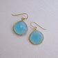 Large blue chalcedony teardrop gemstones bezeled in gold and suspended from earwires. Modeled image.