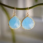 Large blue chalcedony teardrop gemstones bezeled in gold and suspended from earwires. 