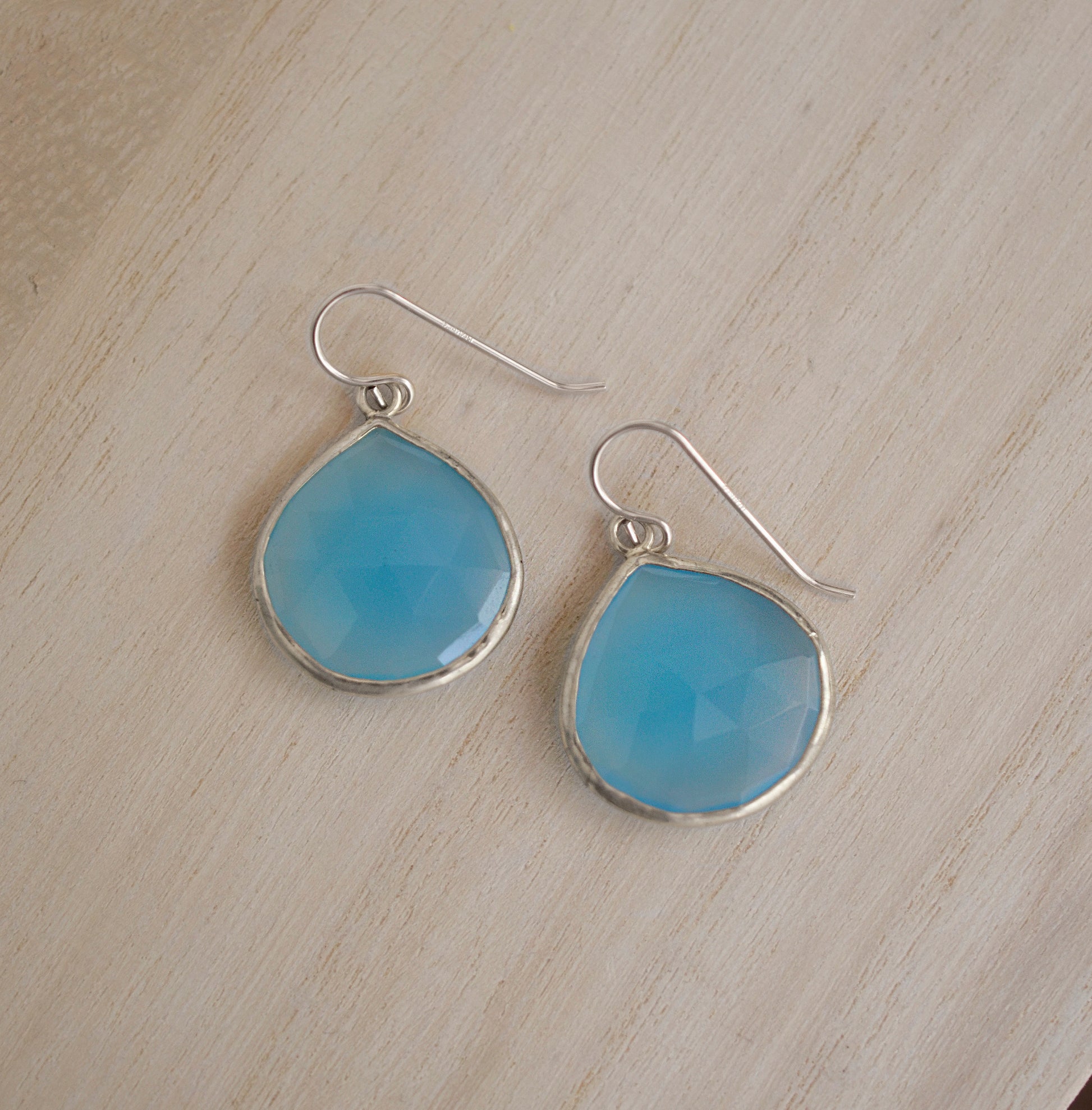Large blue chalcedony teardrop gemstones bezeled in sterling silver and suspended from earwires. 