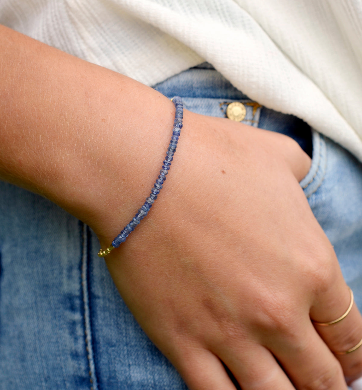 A modeled image of a woman wearing a natural Tanzanite bracelet that has been handmade and beaded with genuine stones, 14k gold filled or sterling silver, and metallic glass beads.