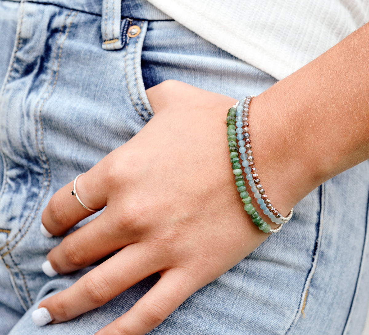 A woman wearing three layered beaded gemstone bracelets. Each bracelet is handmade in Connecticut with natural crystals and is perfect for everyday wear.