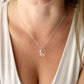 A woman wearing a genuine rose quartz moon crescent necklace in sterling silver. The pendant is a pale, clear pink with natural inclusions. Dainty, minimalist , gemstone jewelry handmade by Gemnia.
